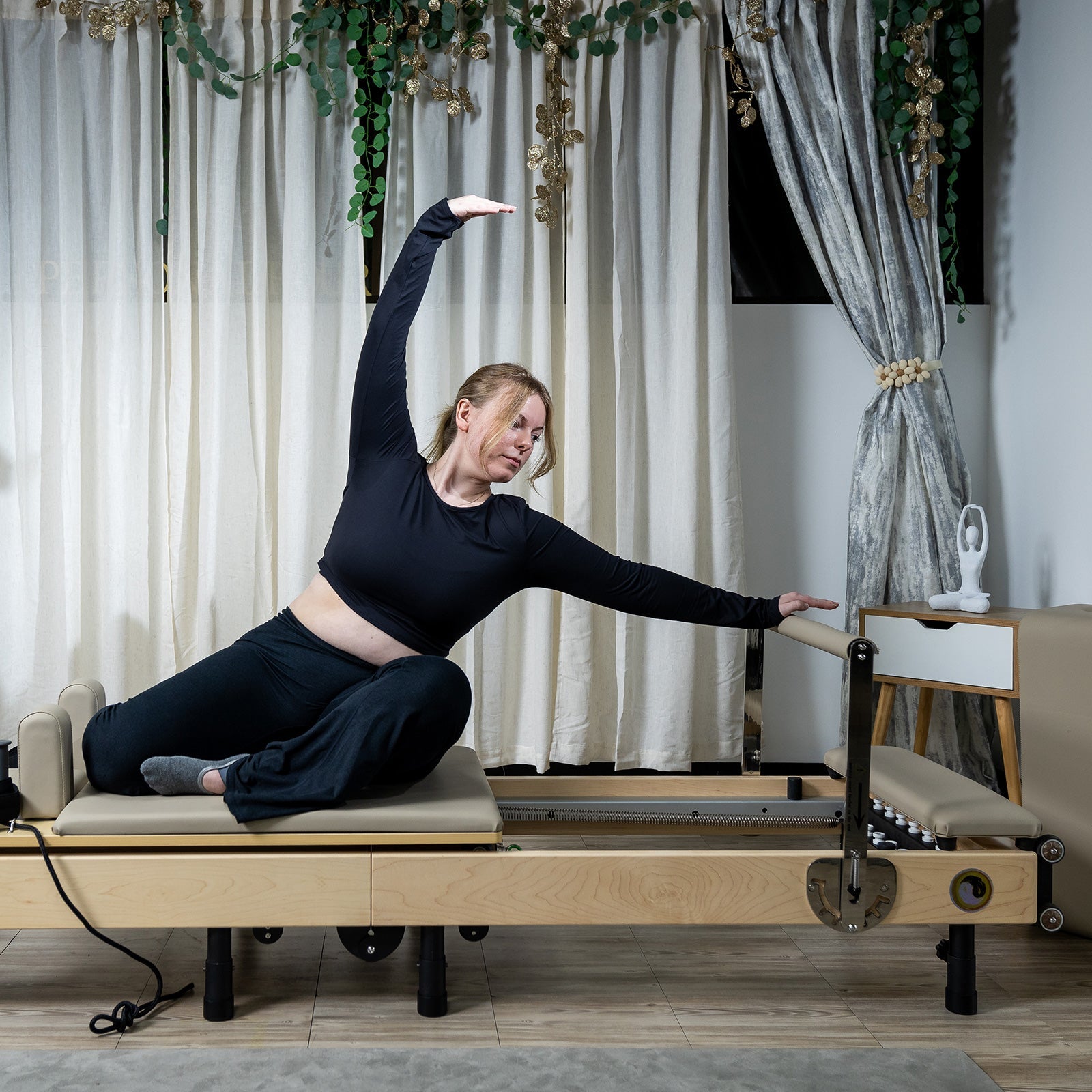 Woman practicing pilates on a reformer machine in a home setting.
